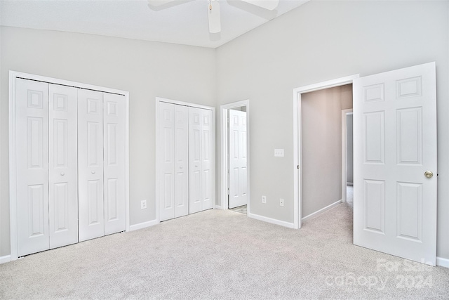 unfurnished bedroom with light carpet, high vaulted ceiling, ceiling fan, and multiple closets