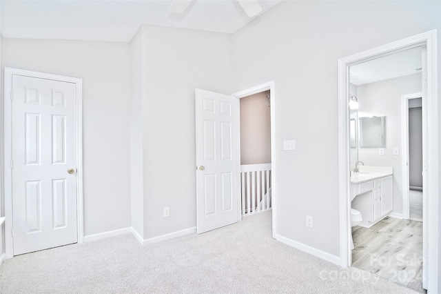 unfurnished bedroom with connected bathroom, ceiling fan, light colored carpet, and lofted ceiling