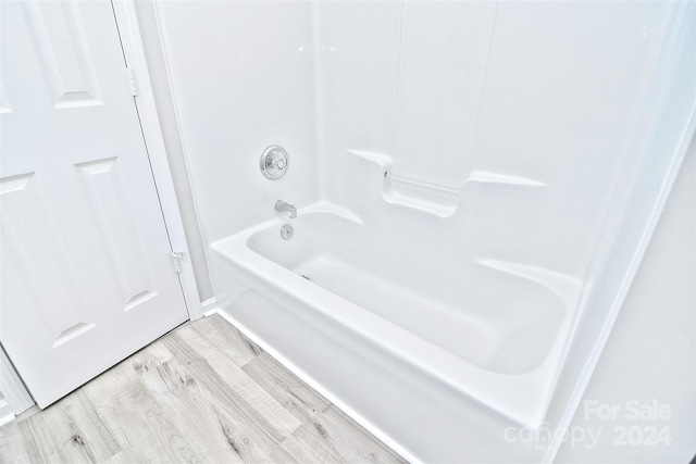 bathroom with hardwood / wood-style flooring and bathing tub / shower combination