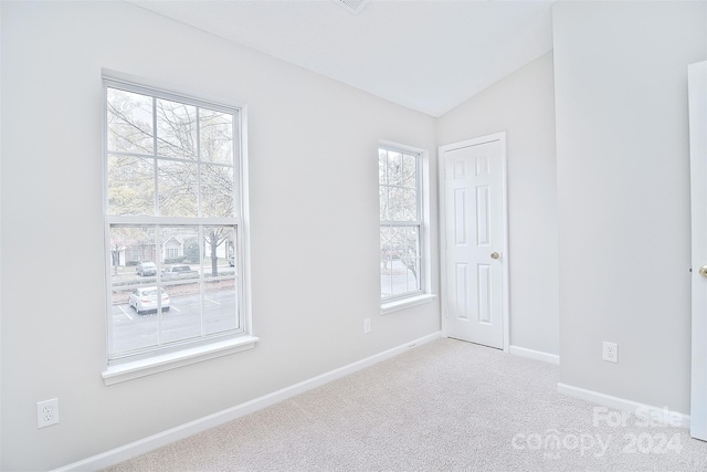 carpeted empty room with vaulted ceiling