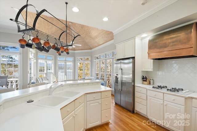 kitchen with white cabinetry, crown molding, stainless steel fridge, and premium range hood