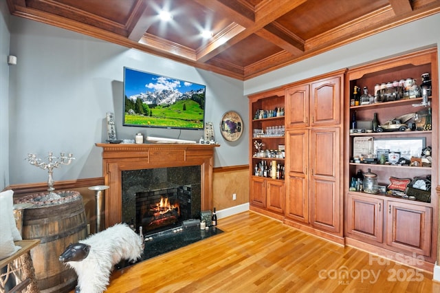 living room with coffered ceiling, ornamental molding, a fireplace, and light hardwood / wood-style flooring