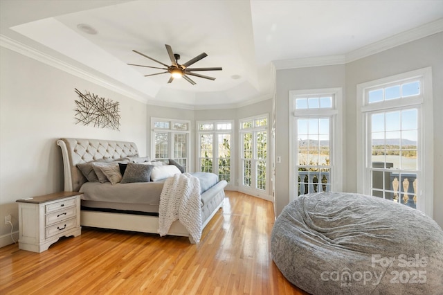 bedroom featuring multiple windows, crown molding, and light wood-type flooring