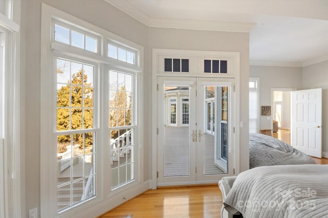 bedroom with crown molding, access to exterior, light hardwood / wood-style floors, and french doors