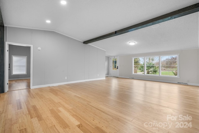 unfurnished living room with vaulted ceiling with beams, light wood-type flooring, and a textured ceiling