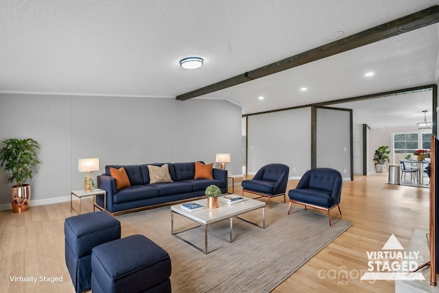 living room with beamed ceiling, a textured ceiling, light hardwood / wood-style flooring, and crown molding