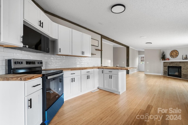 kitchen featuring butcher block counters, white cabinetry, black appliances, and light wood-type flooring