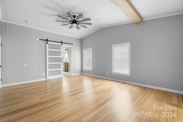 unfurnished bedroom with lofted ceiling with beams, a barn door, a textured ceiling, and light hardwood / wood-style flooring