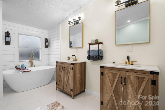 bathroom with a tub, tile patterned flooring, a textured ceiling, wooden walls, and vanity