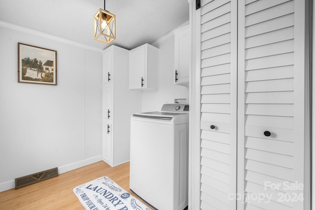 laundry room with cabinets, light wood-type flooring, ornamental molding, a textured ceiling, and washer / dryer