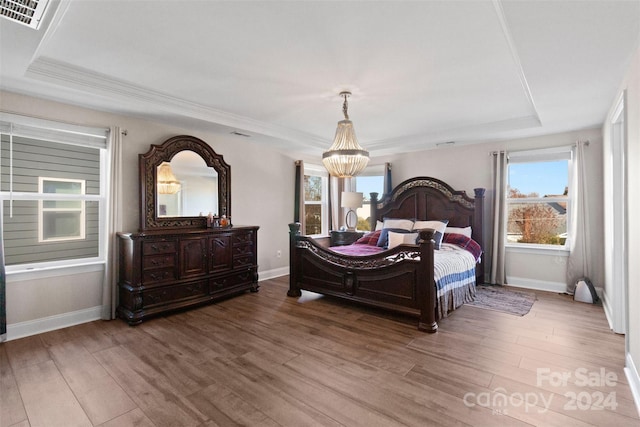 bedroom with a chandelier, hardwood / wood-style floors, a raised ceiling, and ornamental molding