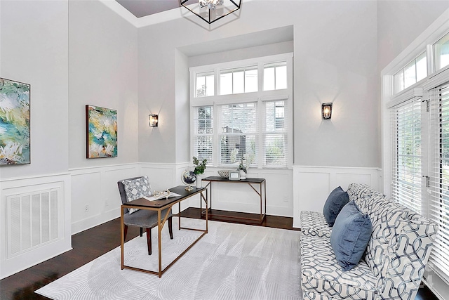 office area featuring a towering ceiling, dark wood-type flooring, and an inviting chandelier