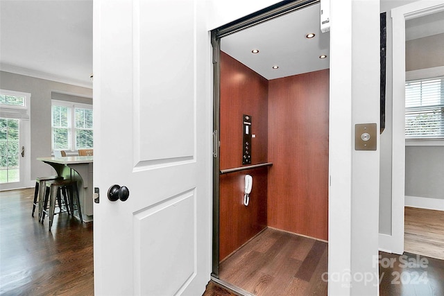 room details featuring wood-type flooring, elevator, and ornamental molding