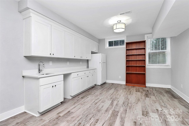 kitchen featuring white refrigerator, light hardwood / wood-style floors, white cabinetry, and sink