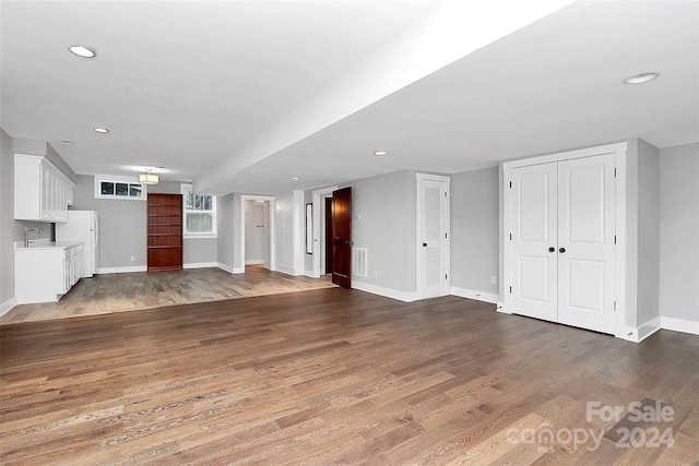 unfurnished living room featuring hardwood / wood-style floors and sink