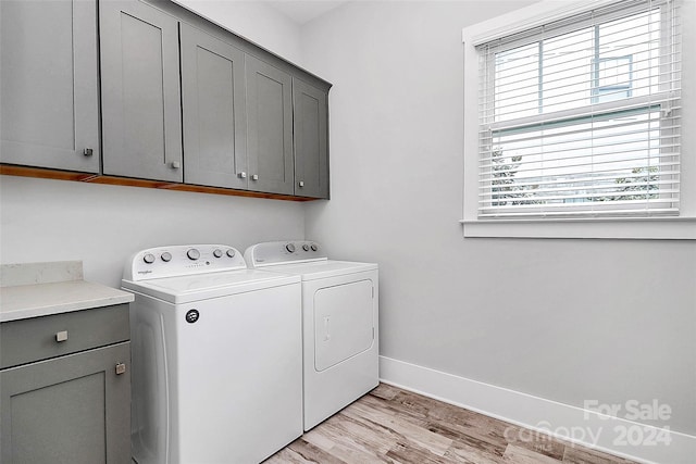 laundry area featuring light hardwood / wood-style floors, cabinets, and washing machine and dryer