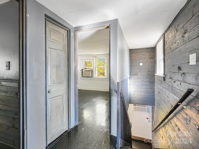 hall featuring dark hardwood / wood-style floors, cooling unit, and wooden walls