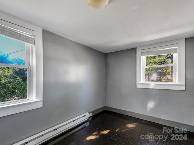 empty room featuring a baseboard radiator and dark hardwood / wood-style floors