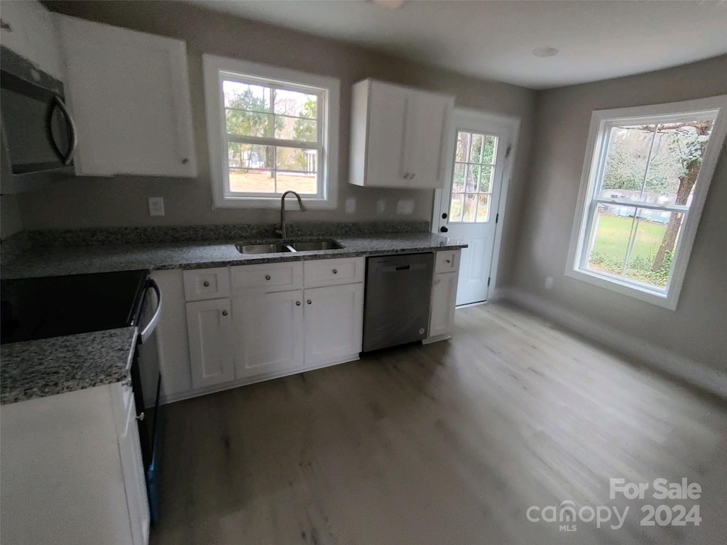 kitchen with dishwasher, white cabinets, sink, stone countertops, and light hardwood / wood-style floors