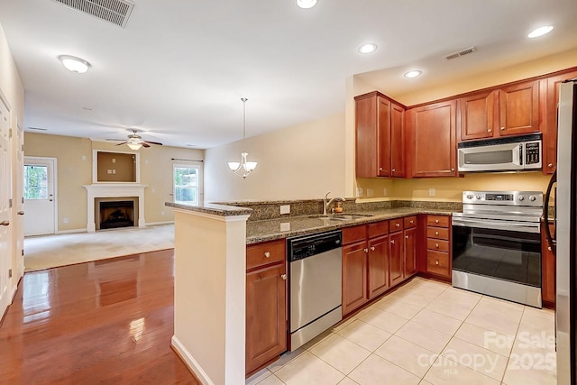 kitchen featuring decorative light fixtures, visible vents, appliances with stainless steel finishes, open floor plan, and a sink