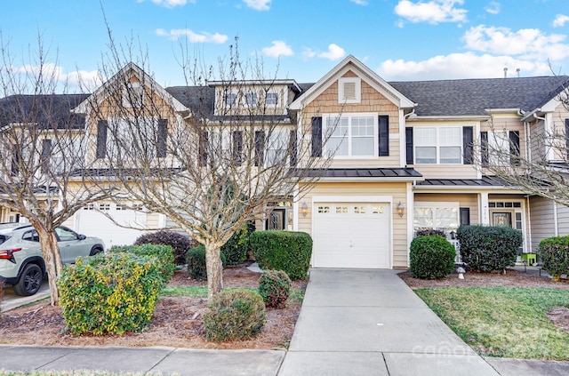 townhome / multi-family property featuring metal roof, driveway, a standing seam roof, and an attached garage