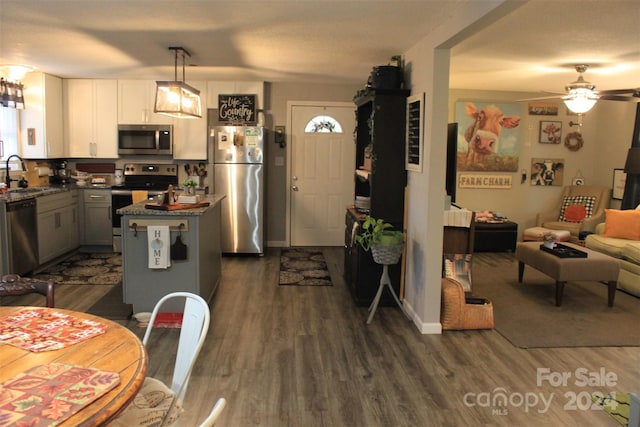 kitchen with pendant lighting, sink, appliances with stainless steel finishes, a kitchen island, and dark hardwood / wood-style flooring