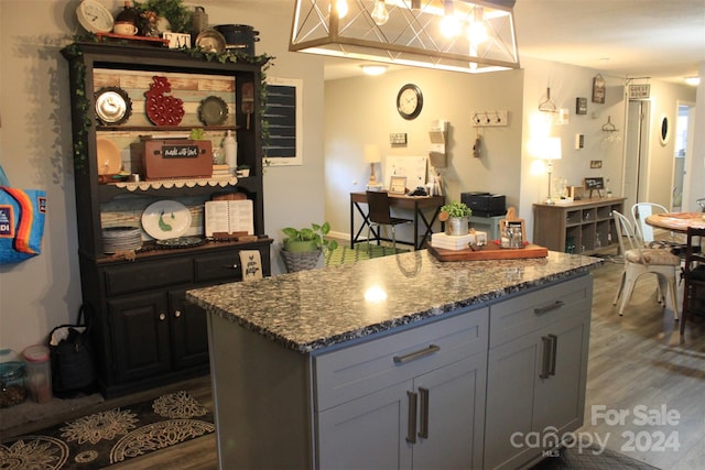 kitchen featuring gray cabinets, dark stone countertops, dark hardwood / wood-style flooring, and a center island