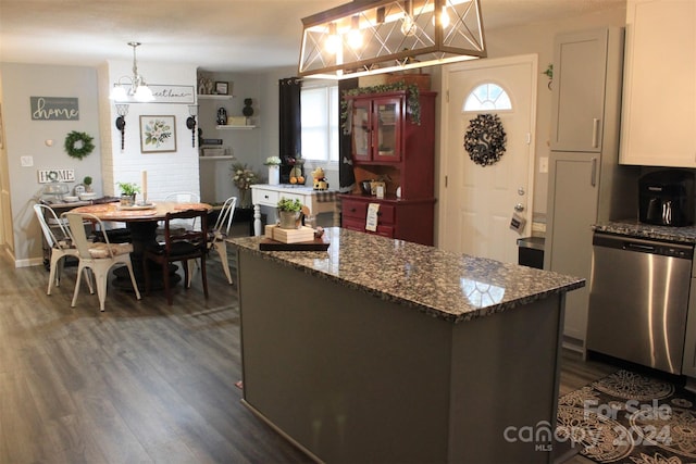 kitchen featuring dark wood-type flooring, white cabinets, hanging light fixtures, stainless steel dishwasher, and a kitchen island