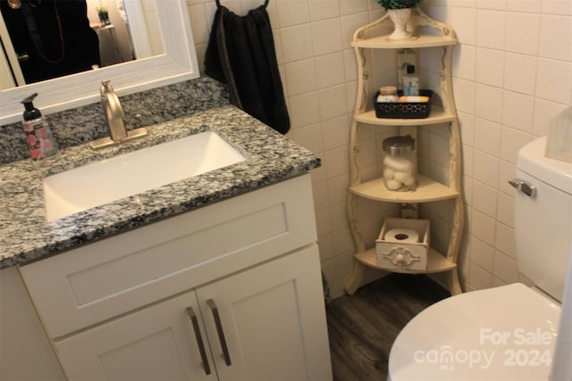 bathroom featuring vanity, wood-type flooring, tile walls, and toilet