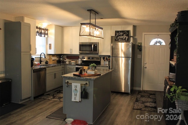 kitchen featuring dark hardwood / wood-style flooring, a center island, a healthy amount of sunlight, and appliances with stainless steel finishes