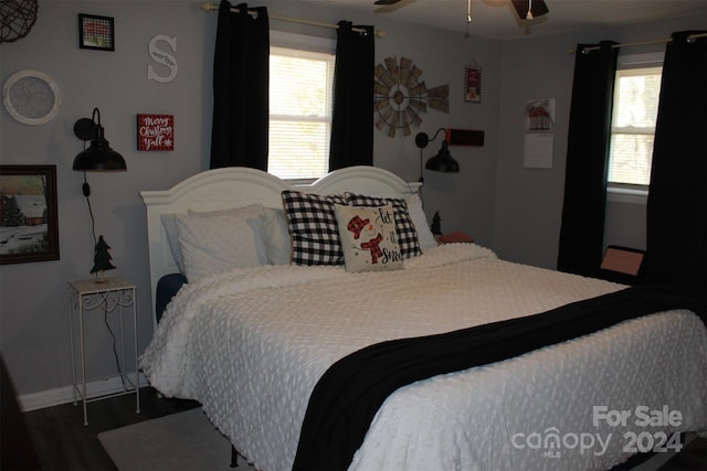 bedroom featuring dark hardwood / wood-style flooring, multiple windows, and ceiling fan