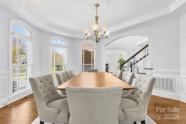 dining room featuring a raised ceiling, crown molding, dark hardwood / wood-style flooring, and a notable chandelier