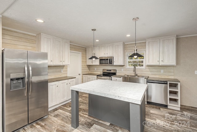 kitchen featuring pendant lighting, a kitchen island, white cabinets, and appliances with stainless steel finishes