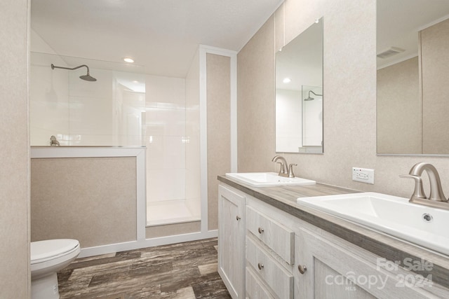 bathroom featuring toilet, hardwood / wood-style floors, vanity, and tiled shower