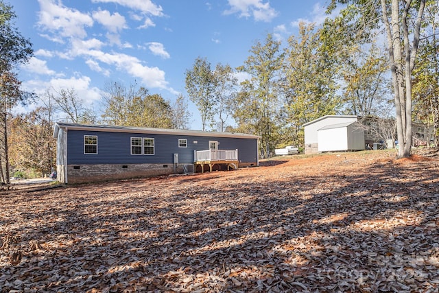 back of property with an outbuilding, a garage, and a wooden deck