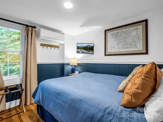 291 Tryon Bay Cir, Lake Lure, NC 28746 - bedroom featuring a wall unit AC, wood finished floors, and wainscoting