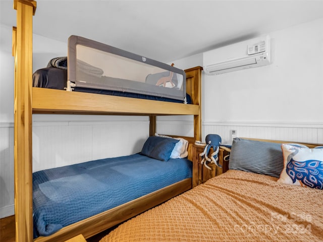 bedroom featuring a wall mounted air conditioner and wood walls