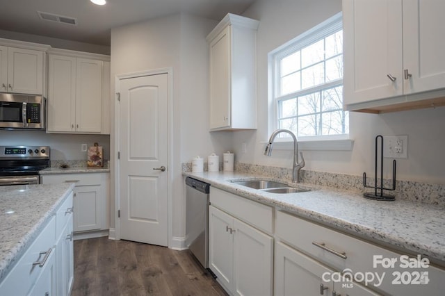 kitchen with appliances with stainless steel finishes, white cabinets, light stone counters, and sink