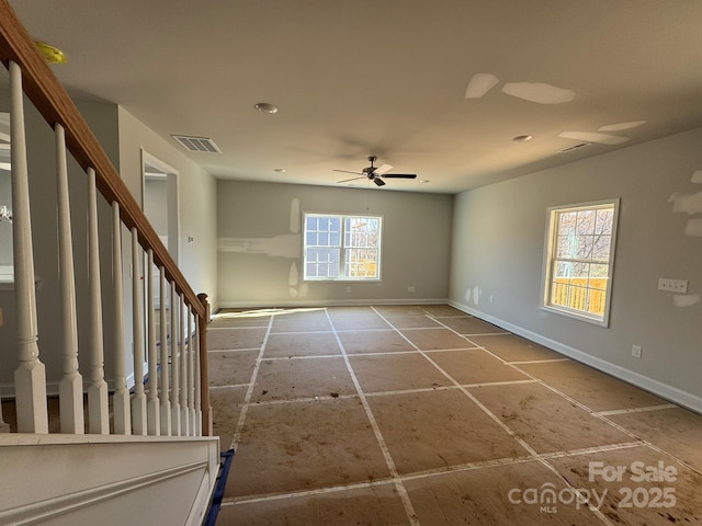 empty room with a ceiling fan, visible vents, baseboards, and stairs