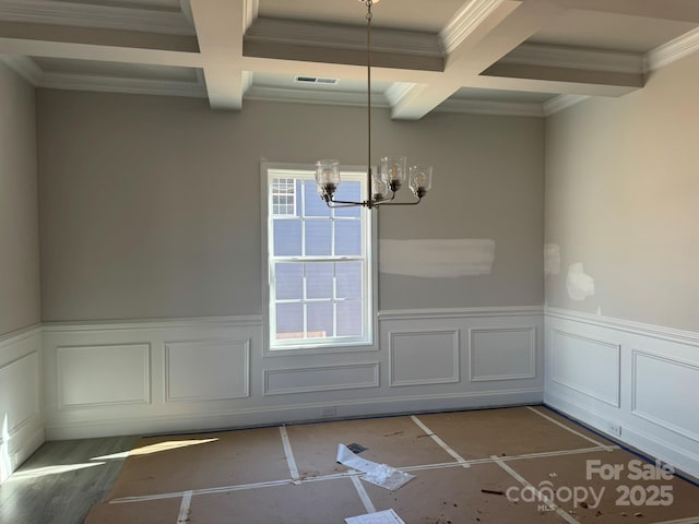 unfurnished dining area with coffered ceiling, a wainscoted wall, and visible vents