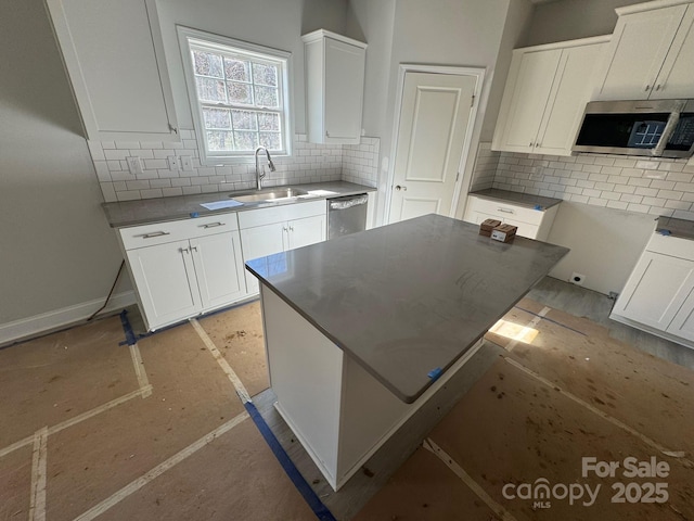 kitchen featuring stainless steel appliances, a sink, white cabinetry, and decorative backsplash