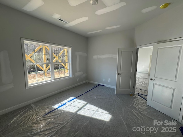 unfurnished bedroom with baseboards, visible vents, and vaulted ceiling