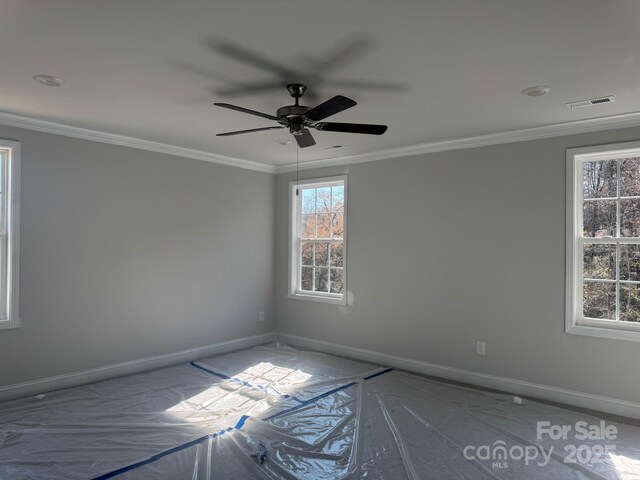 unfurnished room with baseboards, visible vents, and ornamental molding