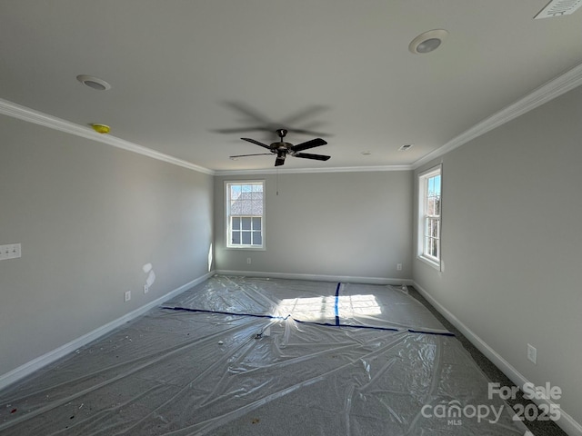 unfurnished room featuring a wealth of natural light, visible vents, crown molding, and baseboards