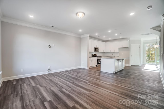 kitchen featuring appliances with stainless steel finishes, open floor plan, white cabinetry, and a center island with sink