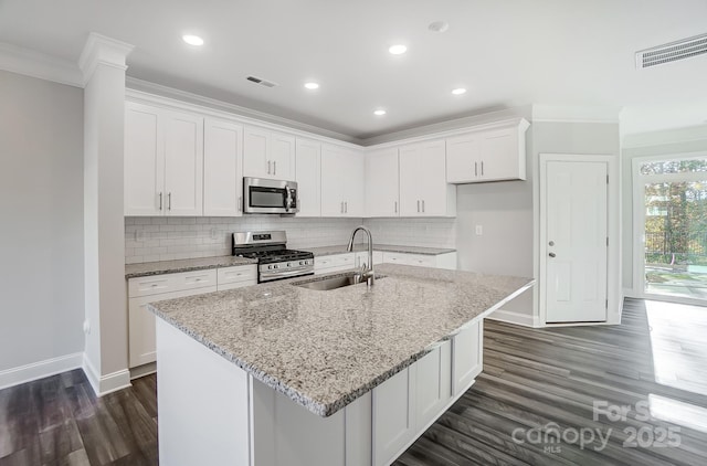 kitchen with white cabinets, light stone counters, appliances with stainless steel finishes, a kitchen island with sink, and a sink