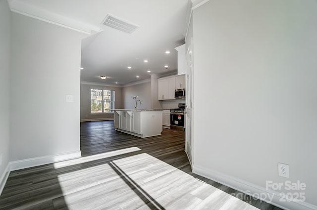 kitchen featuring a center island with sink, visible vents, appliances with stainless steel finishes, a kitchen bar, and white cabinetry