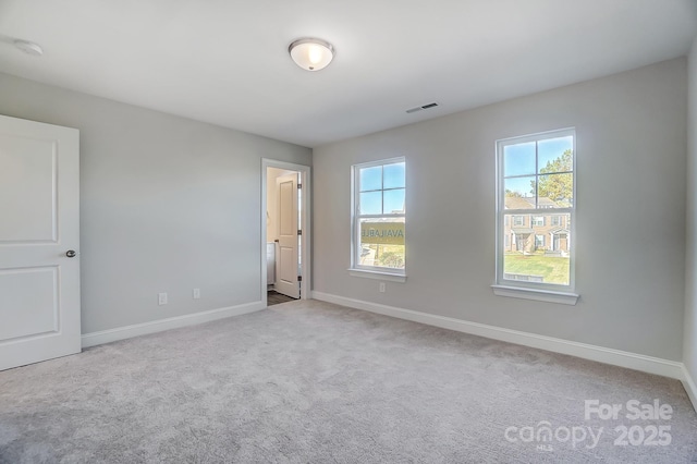 spare room with baseboards, visible vents, and light colored carpet