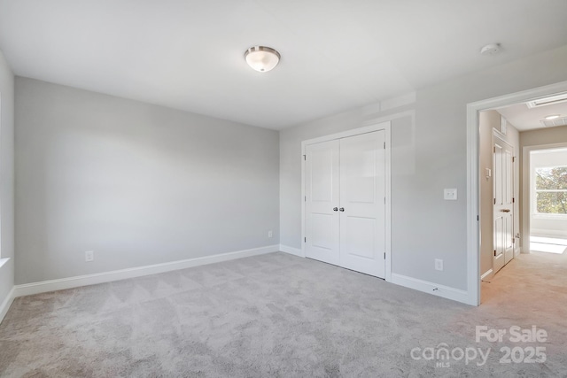 unfurnished bedroom featuring a closet, light colored carpet, visible vents, and baseboards