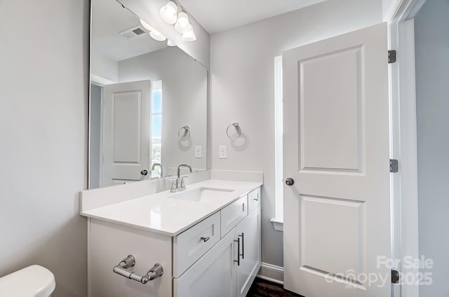 half bath featuring toilet, visible vents, and vanity